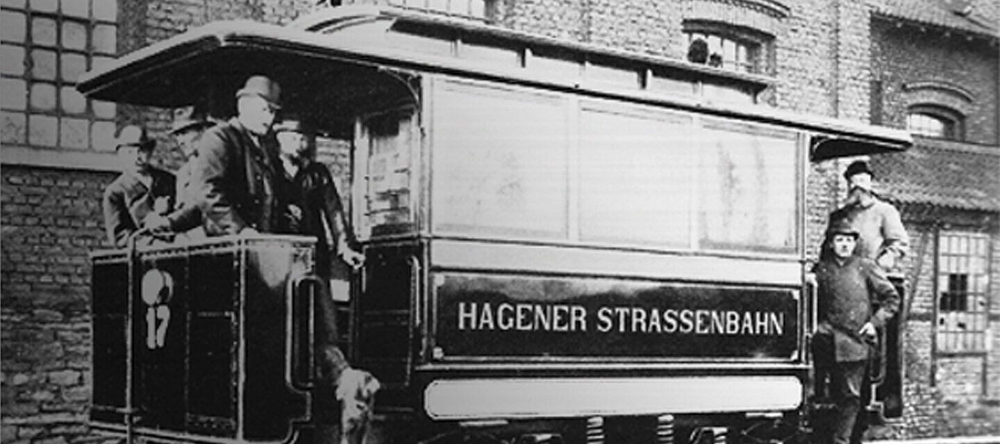Historic black-and-white photo of Hagener Strassenbahn tram number 17 with men in hats and a boy standing beside it