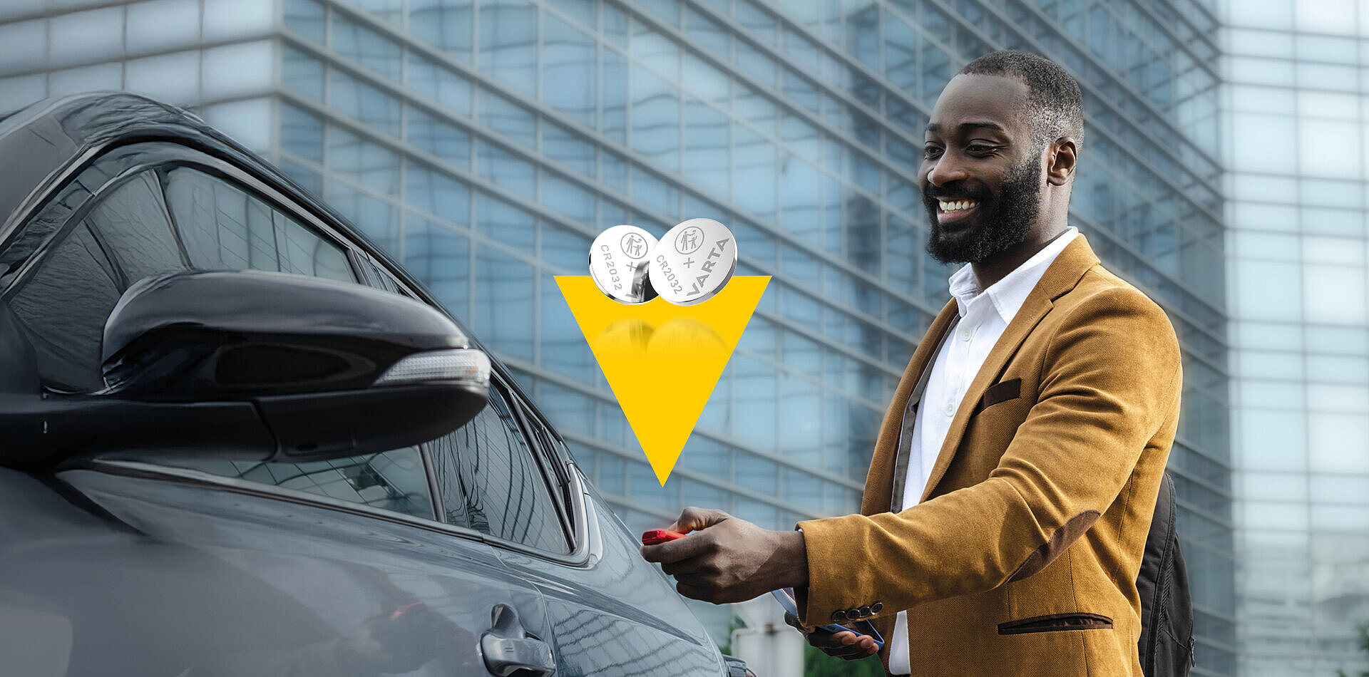 Smiling man in mustard blazer unlocks black car with key fob, two Varta CR2032 batteries shown above in yellow triangle