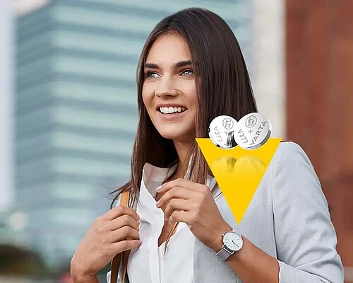 Smiling woman with long brown hair holding two Varta button cell batteries, wearing white blouse and wristwatch