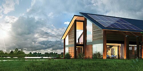 Modern wooden barn-style house with large solar panels on sloped roof, illuminated interior, beside lake under cloudy sky