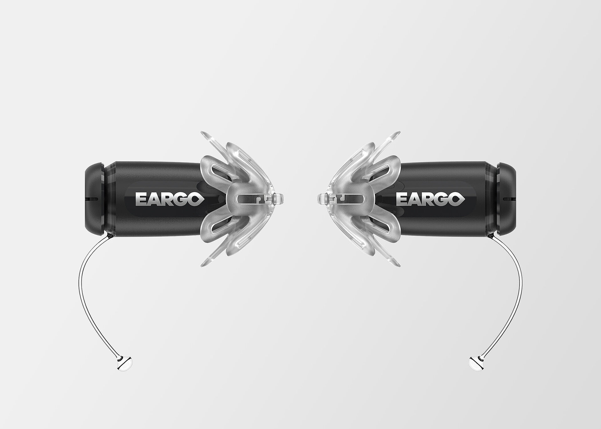 Two black Eargo hearing aids with translucent flexible fittings and thin removal wires, facing each other on grey background