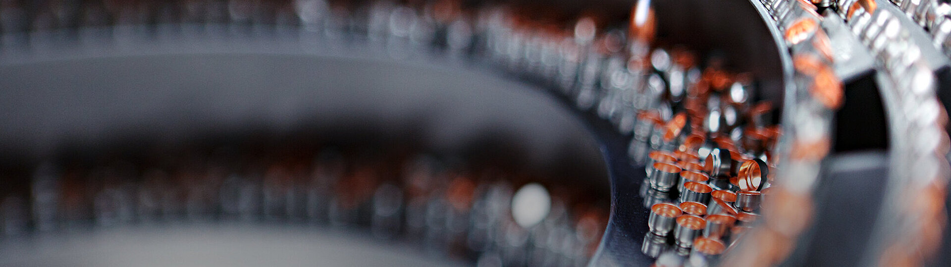 Close-up of pharmaceutical vials with orange caps arranged in curved rows on a production line, with shallow depth of field