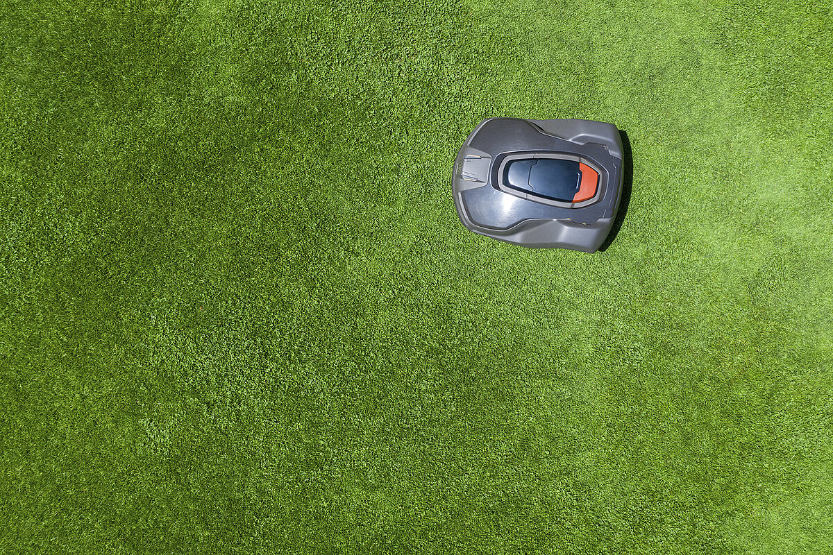 Top-down view of a grey robotic lawn mower on a green lawn