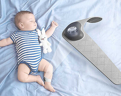Sleeping baby in striped bodysuit with plush bunny beside a baby monitor device on light blue bedding