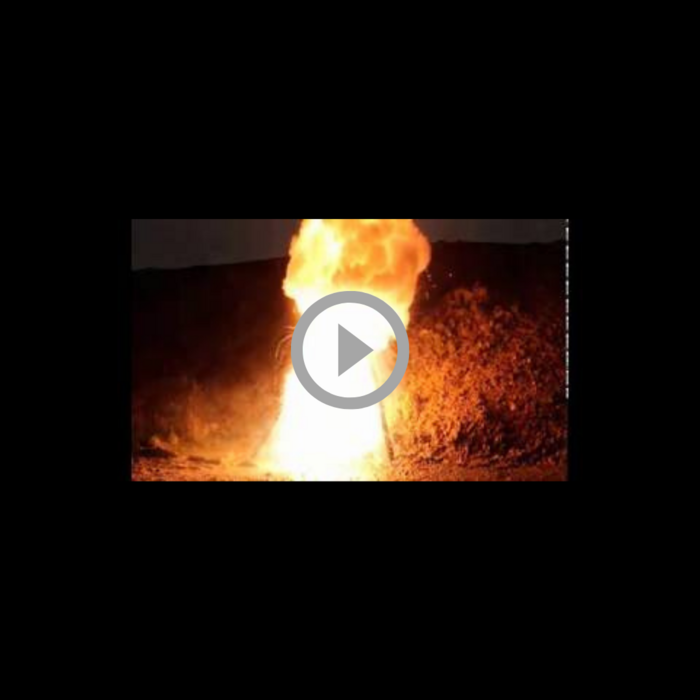 Video thumbnail showing a tall plume of fire burning at night with a play button overlay in the center