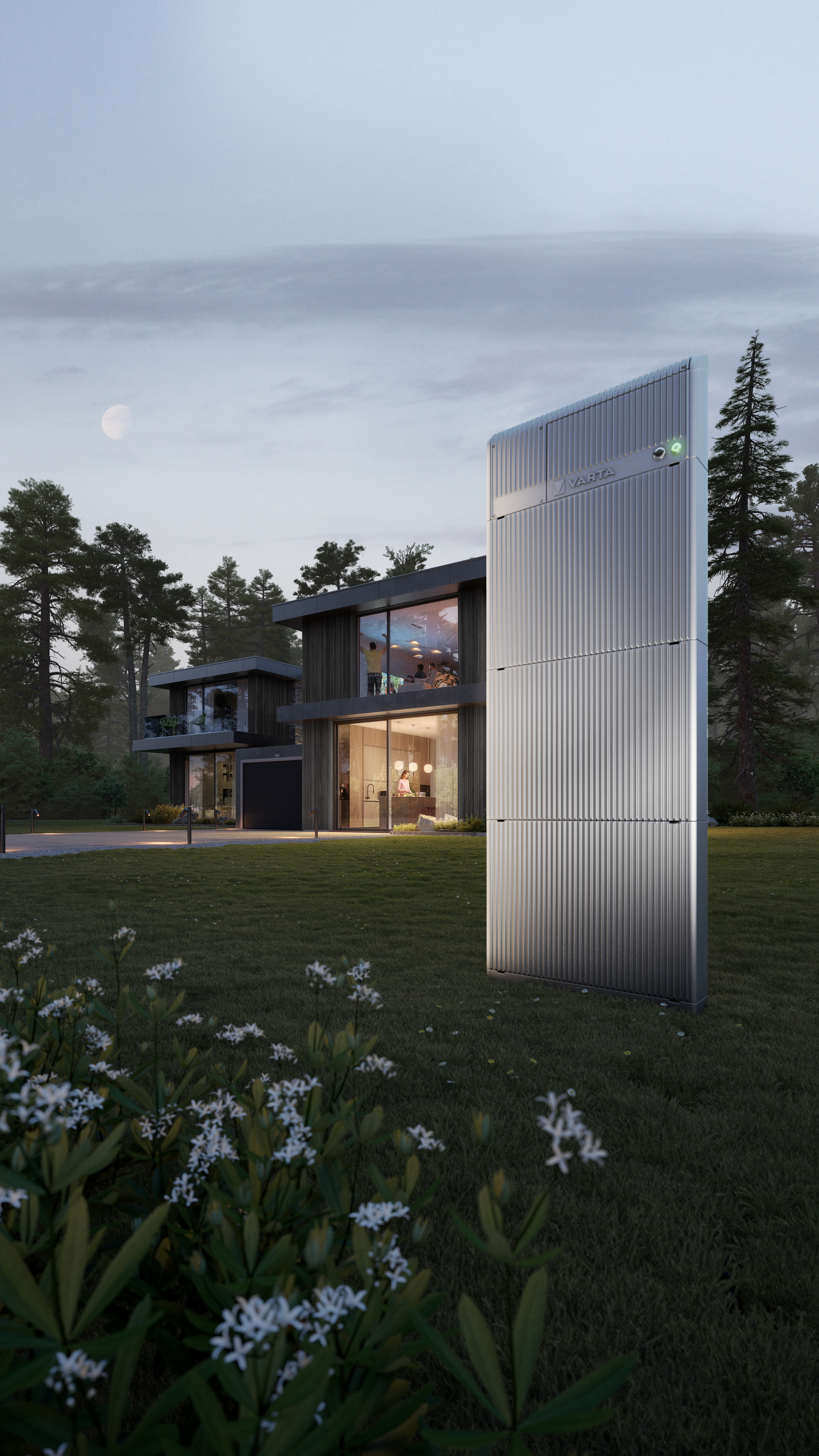 Hoher silberner VARTA-Energiespeicher auf Rasen vor modernem Haus mit beleuchteter Küche, Wald und Mond in Dämmerung